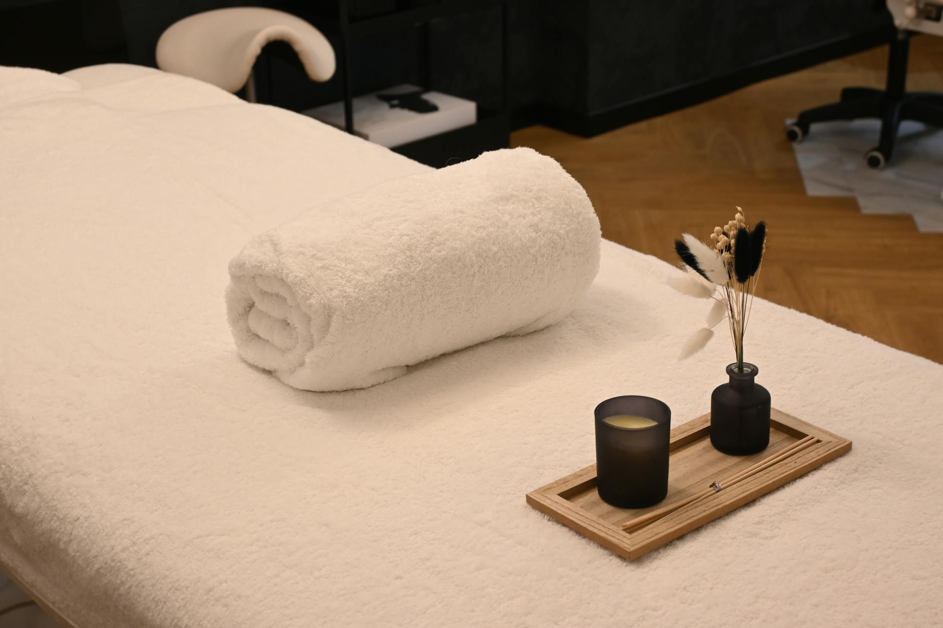 une table de massage de spa sereine amenagee avec une serviette roulee une bougie et des vases decoratifs dans un environnement relaxant