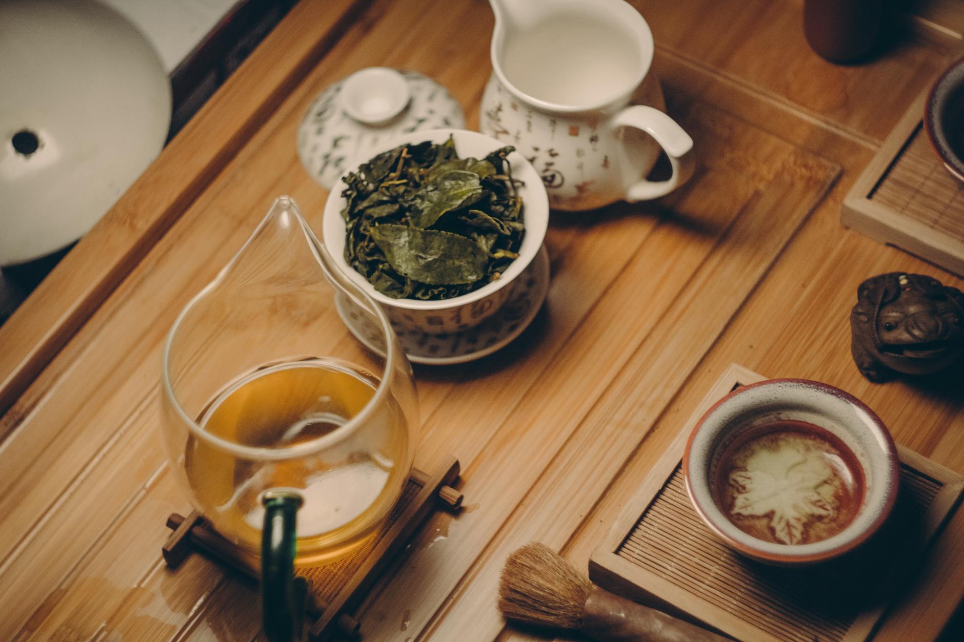 theiere en ceramique blanche a cote de la tasse avec des feuilles