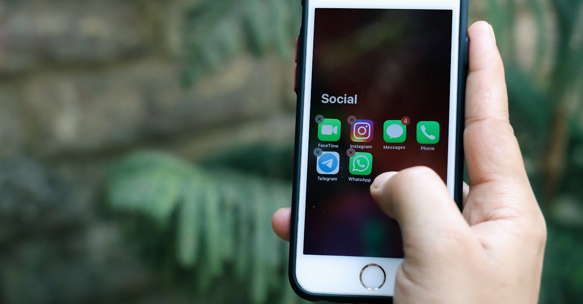 close up of a hand holding a smartphone displaying social media apps outdoors