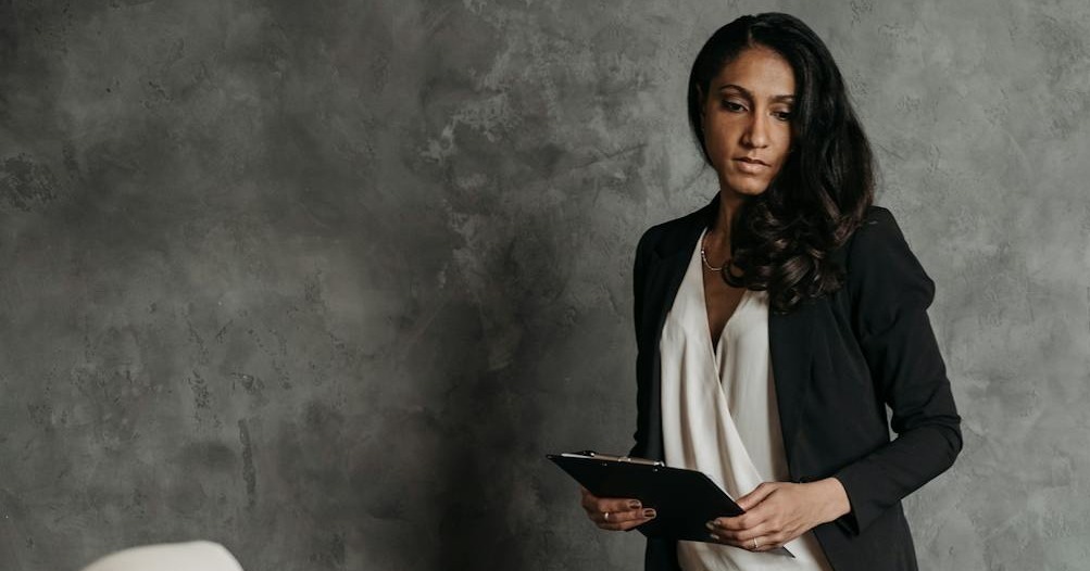 confident businesswoman in a formal setting with legal papers and a statue of justice on the desk