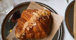 A tasty almond croissant with coffee on a table for a cozy cafe breakfast