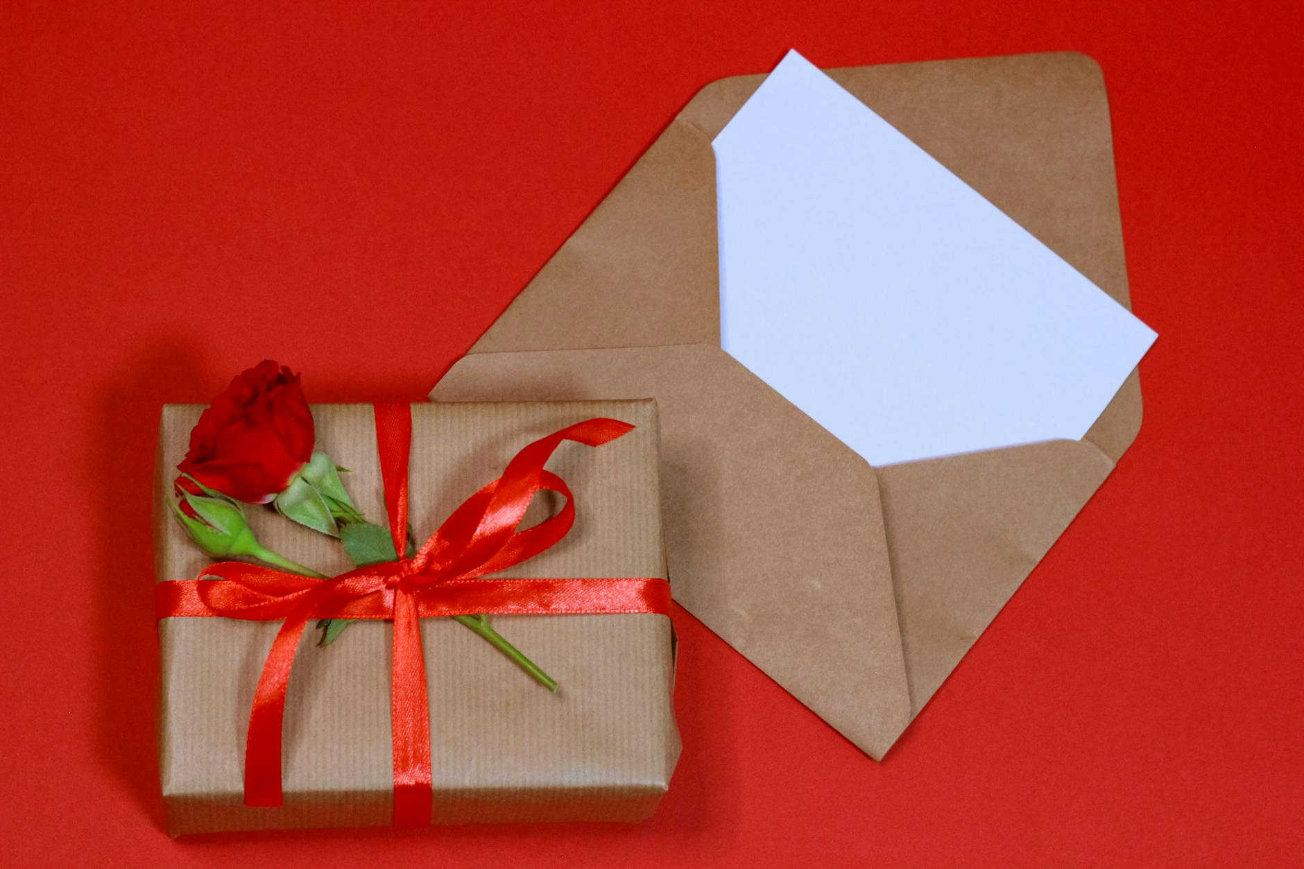 un coffret cadeau joliment emballe avec une rose rouge sur un fond rouge vif parfait pour les celebrations