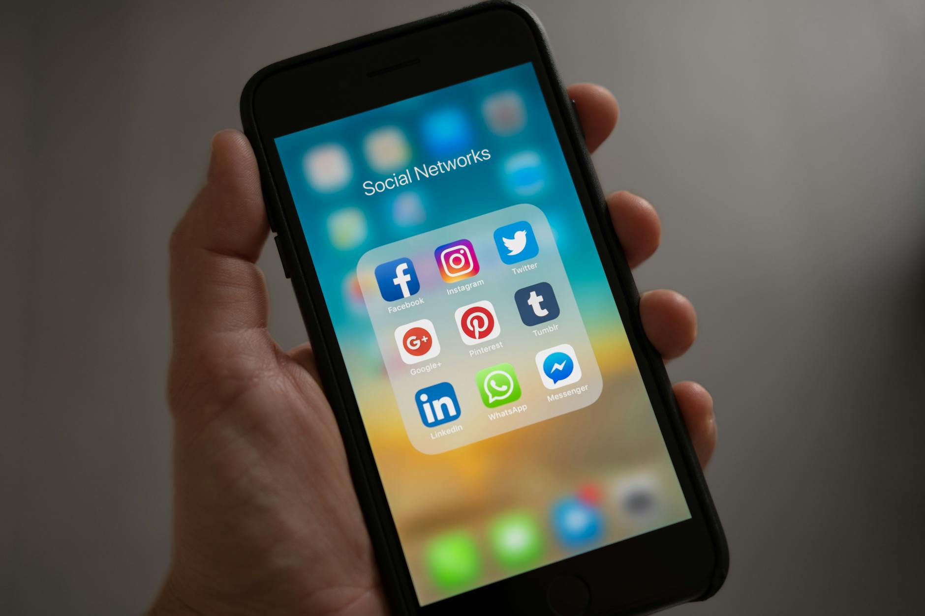 personne tenant iphone montrant le dossier de reseaux sociaux