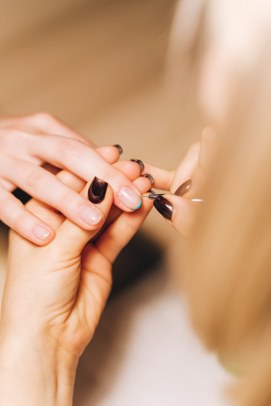 personne tenant du vernis a ongles noir
