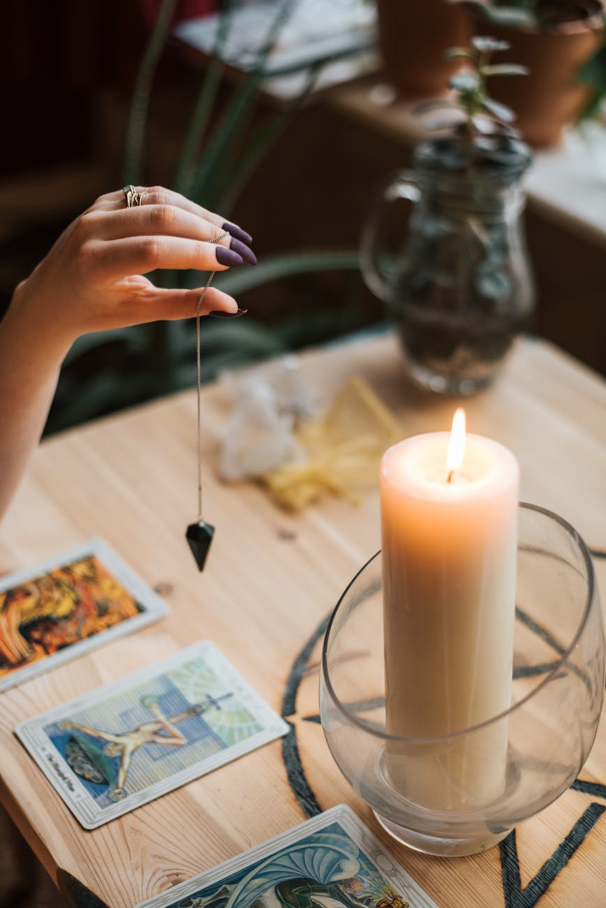 devin de culture avec talisman et cartes de tarot pres de bougie rougeoyante
