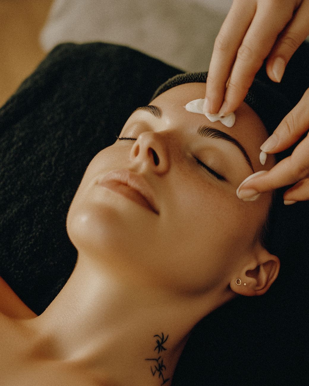 un therapeute professionnel applique delicatement de la creme sur le visage d une femme