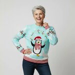 Vrouw in lichtblauwe kersttrui met jonglerende pinguin en ledlampjes