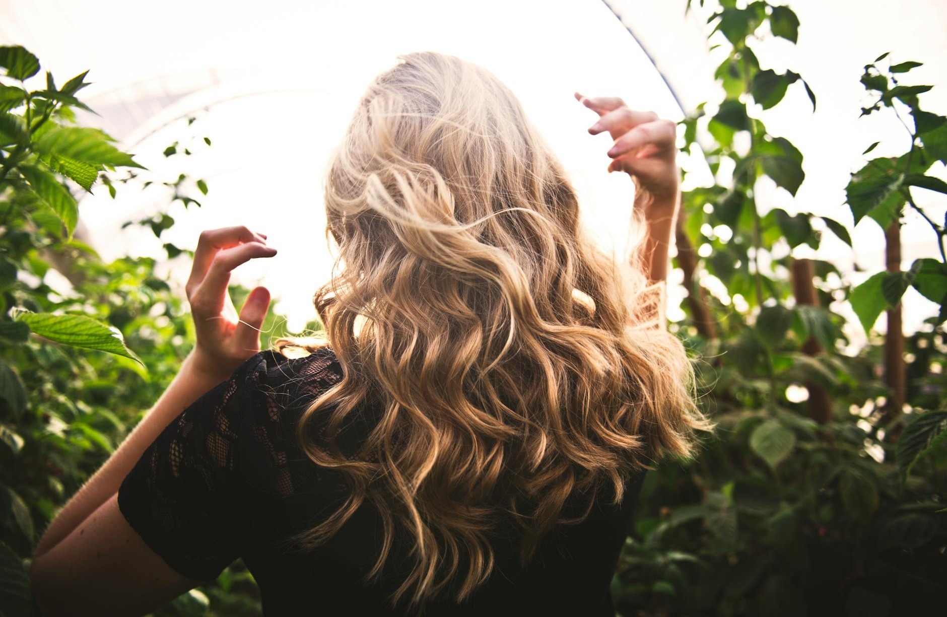 femme aux cheveux blonds debout entre les plantes vertes
