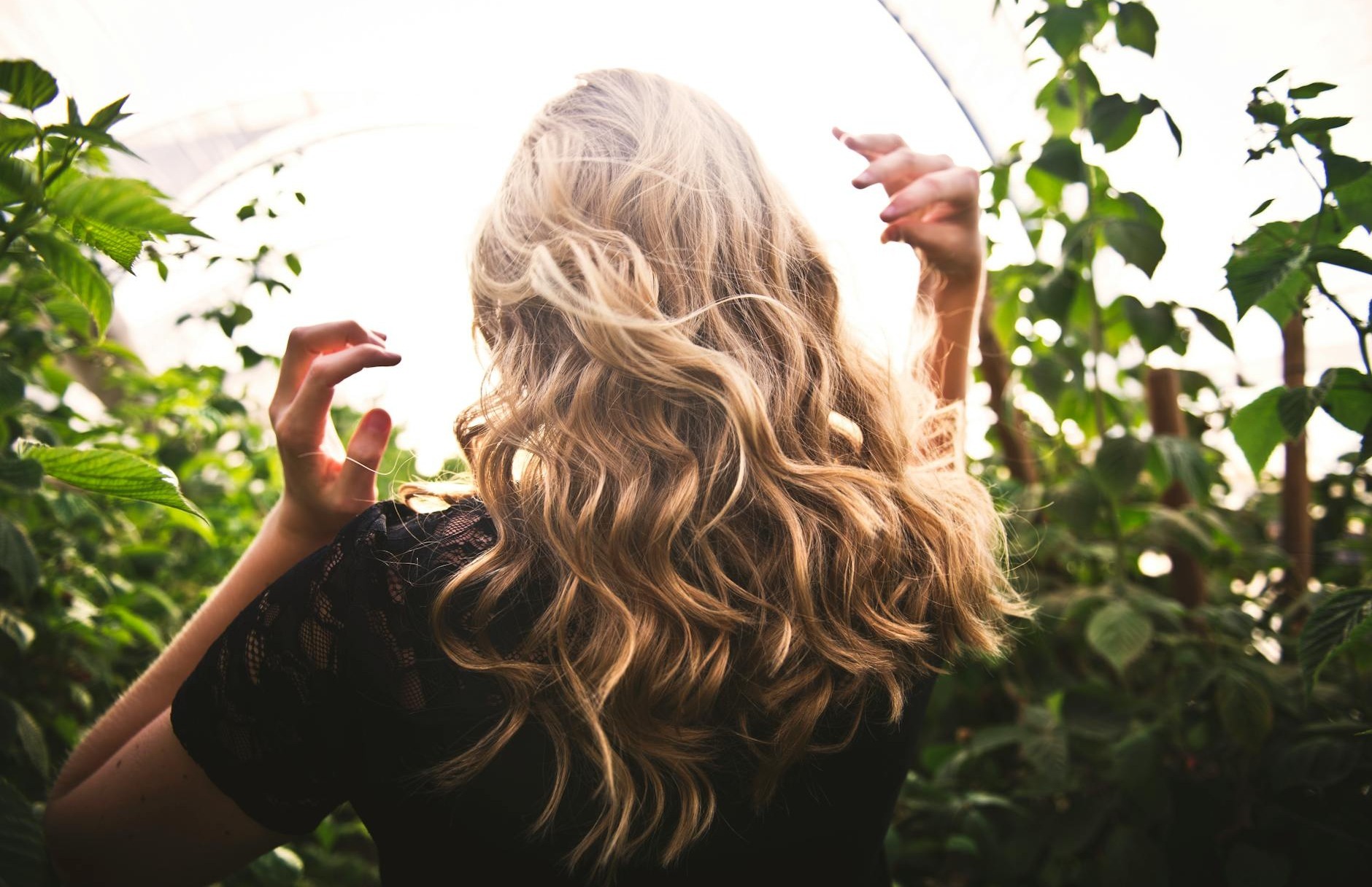 femme aux cheveux blonds debout entre les plantes vertes