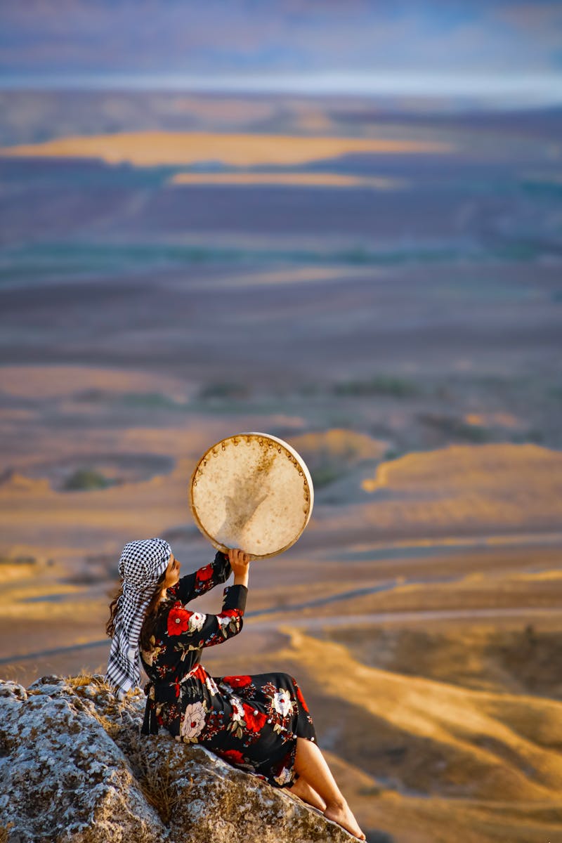 femme en tenue traditionnelle jouant du tambour sur une falaise au coucher du soleil adiyaman turkiye