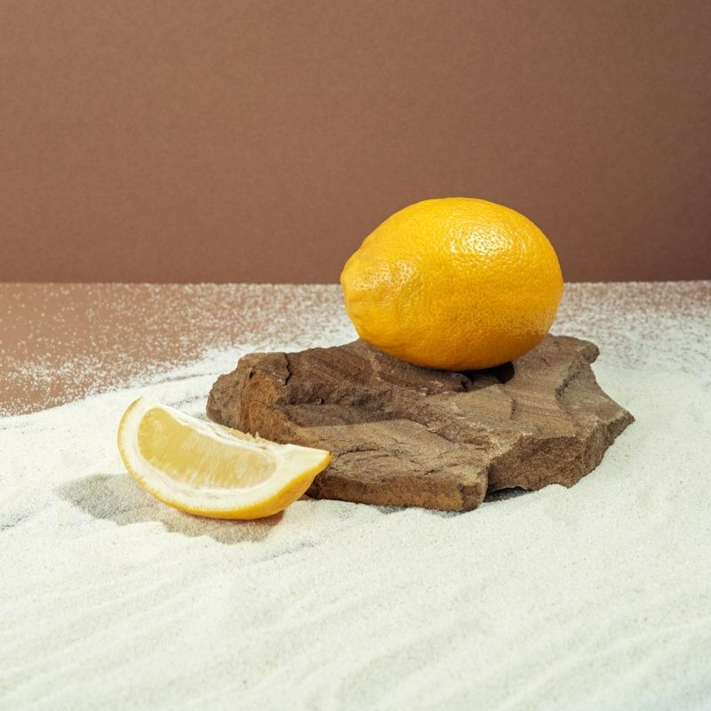 Un citron frais et une tranche sur une surface en bois avec du sable blanc et un fond brun