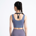 Photo produit e-commerce professionnelle ultra claire et stylée _ femme de dos portant un appareil de massage noir en forme de Y sur le cou_épaules, tenue de sport moderne bleu-gris et violet, sur fond blanc pur é