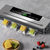 Machine d'emballage sous vide gris argenté sur surface gris béton. Gâteaux de lune jaunes et verts sous vide sortant de la machine. Écran LED vert affichant _88_. Panneau tactile _Vacuum Sealer_ avec boutons Vac,