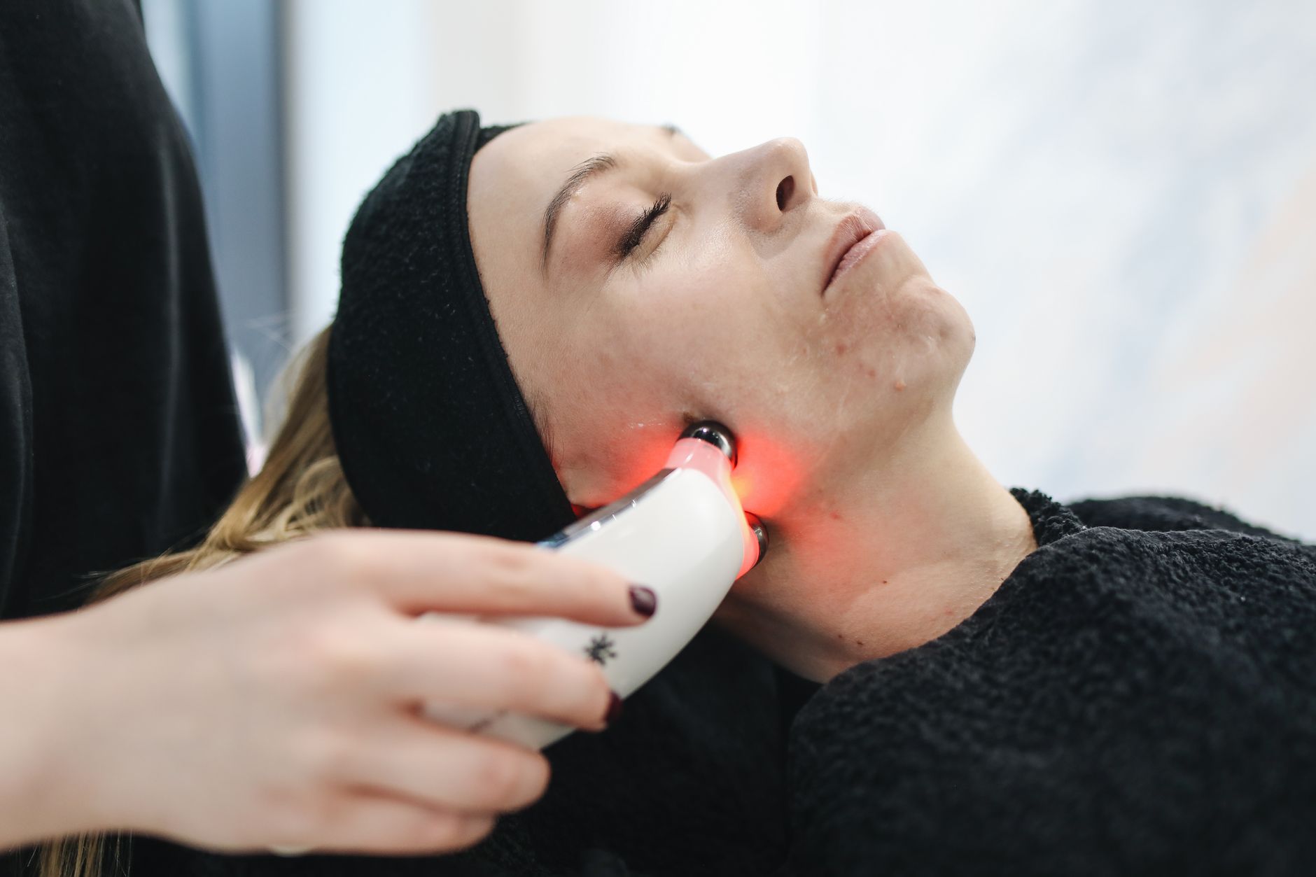 une femme adulte recoit un traitement facial au laser dans une clinique moderne de soins de la peau