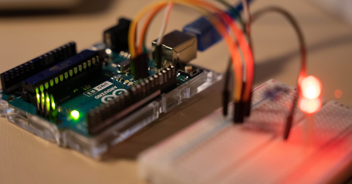 close up of arduino microcontroller connected to a breadboard with a glowing led
