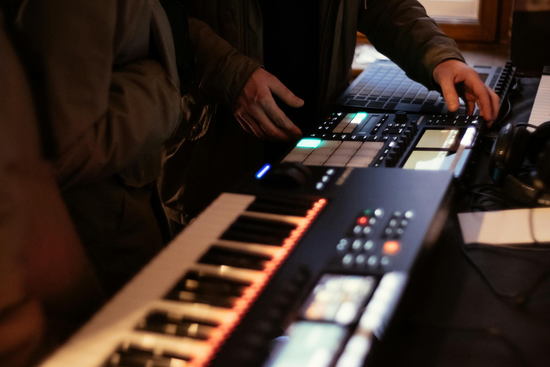music producer using synthesizer and beat pad in studio setting