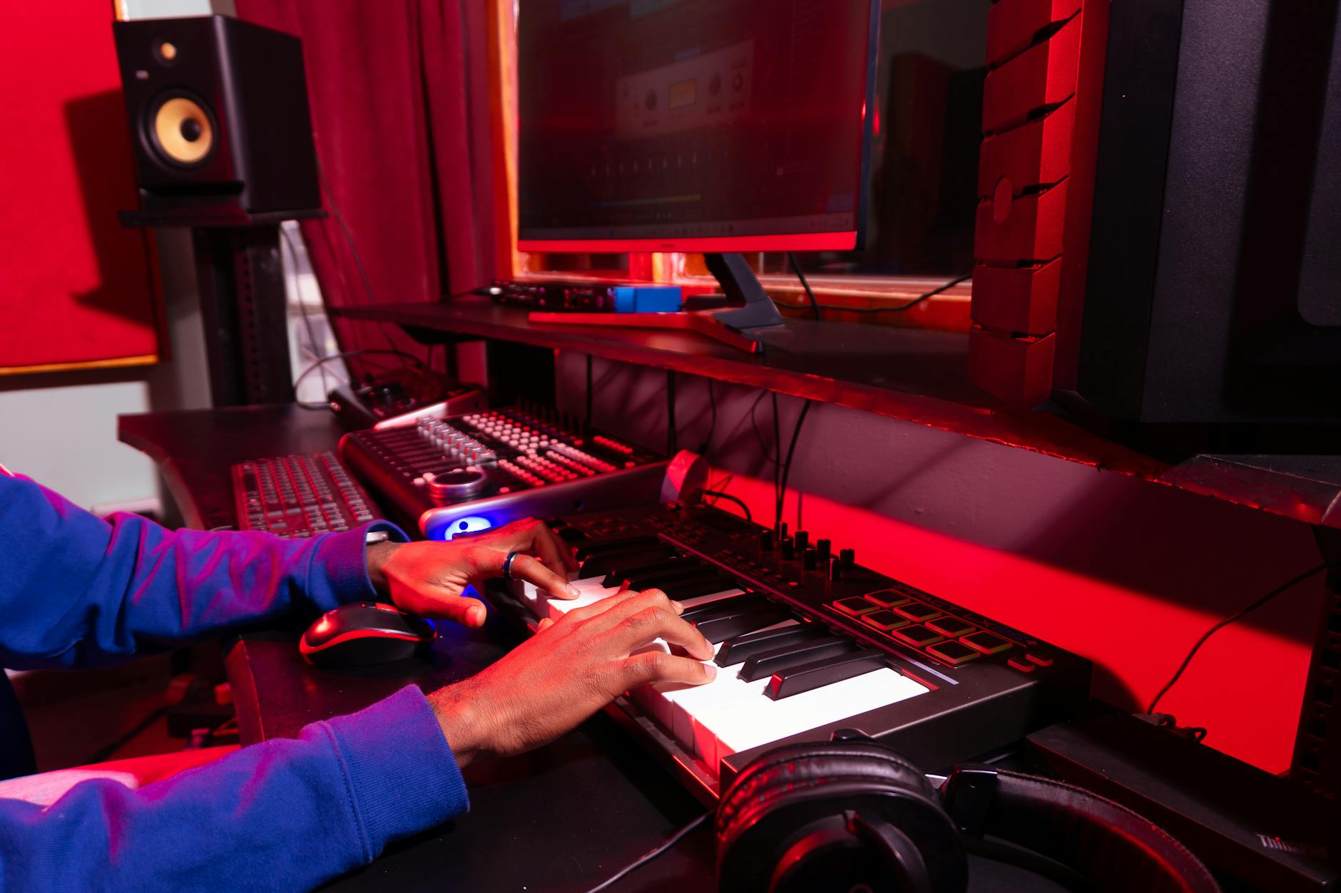 a person creating electronic music in a modern studio using a midi controller and computer