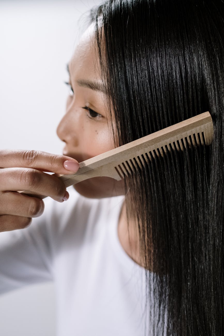 femme en chemise blanche a col rond tenant un peigne a cheveux