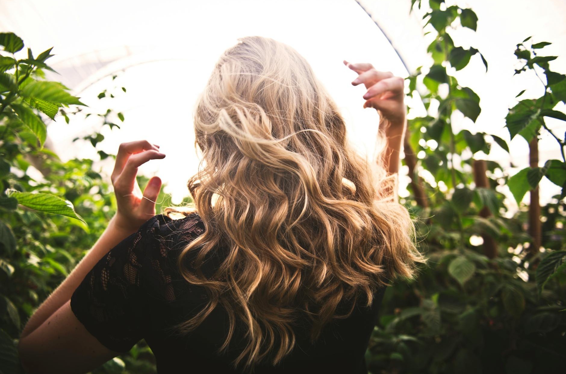 femme aux cheveux blonds debout entre les plantes vertes