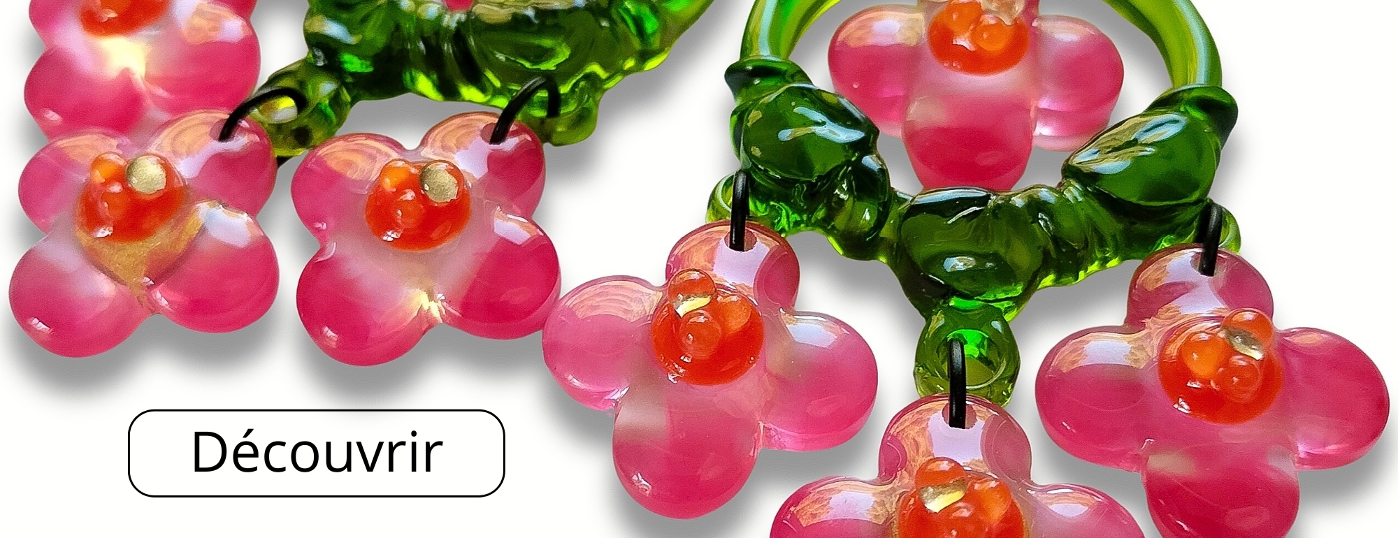 Grandes boucles d'oreilles à fleurs roses, cœurs orange et or suspendues à des créoles vertes. 