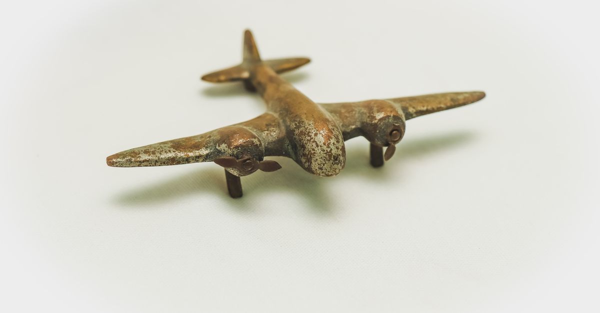 close up of a vintage rusty metal toy airplane with propellers on a plain background