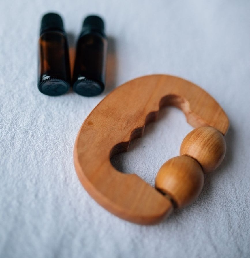 gros plan sur des bouteilles d huile essentielle et un masseur en bois sur une surface douce