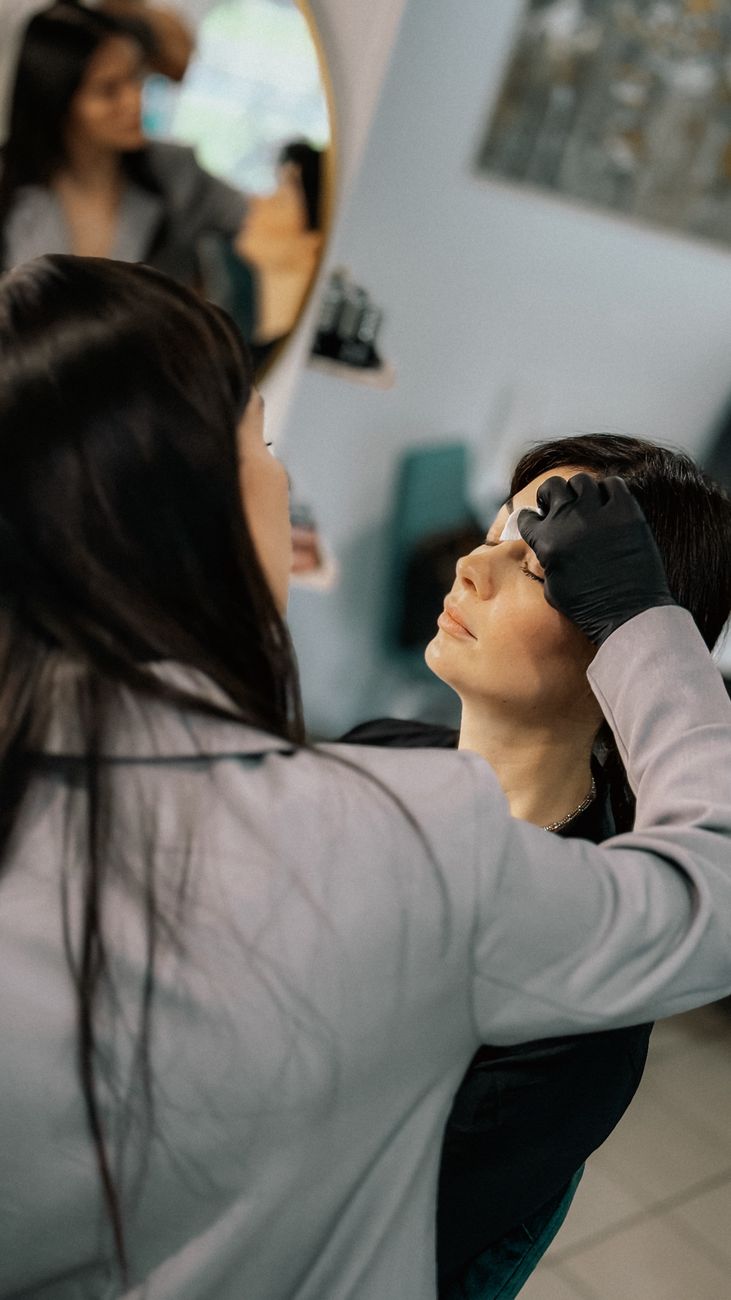 maquilleuse appliquant soigneusement du maquillage aux sourcils sur une cliente dans un salon