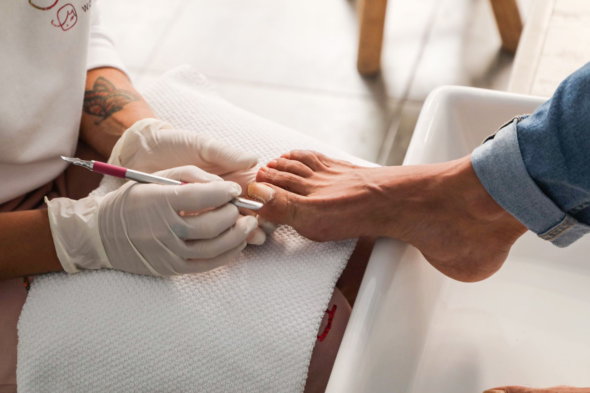 seance de pedicure montrant des mains gantees effectuant des soins des ongles sur le pied