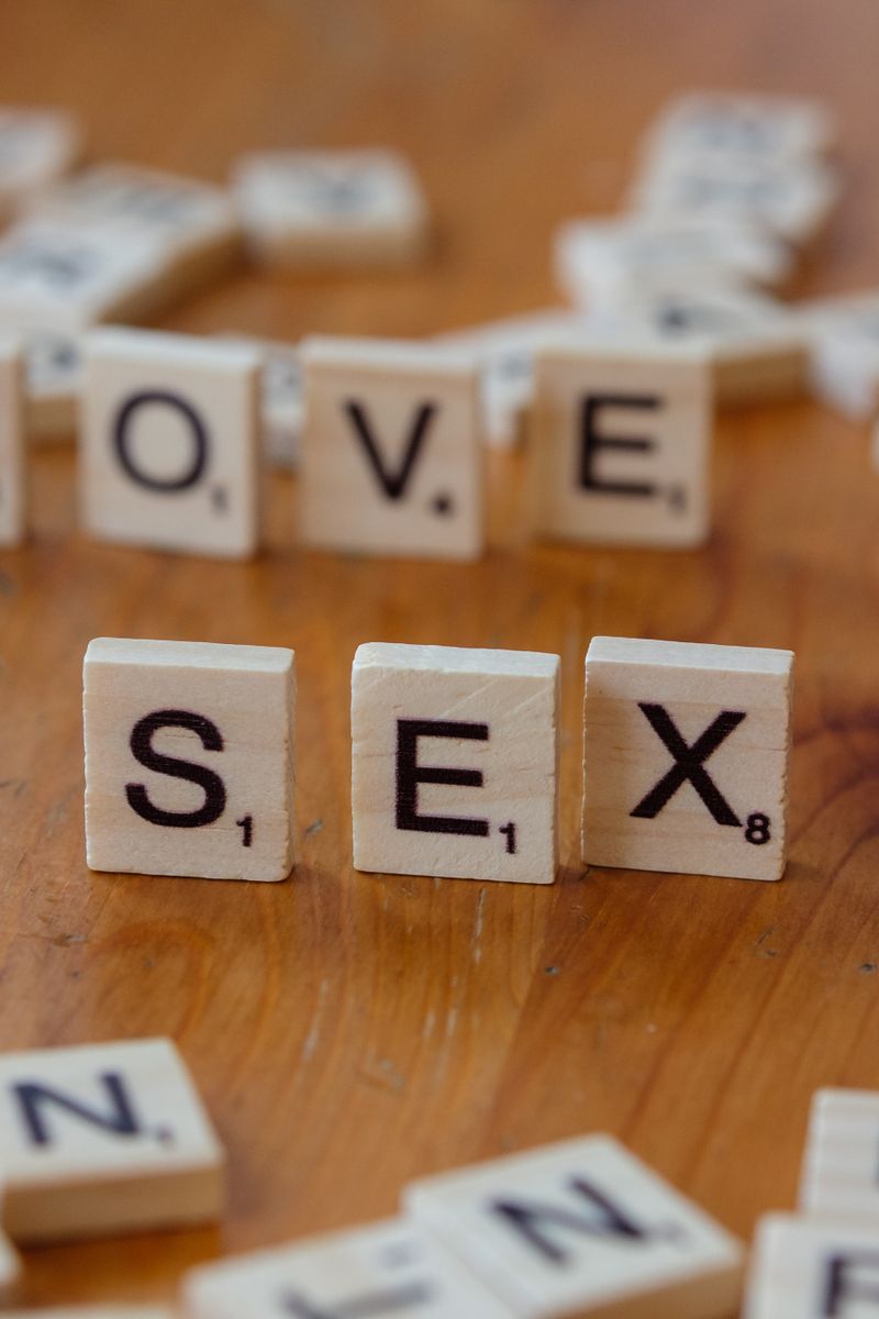 des lettres de scrabble epelant amour et sexe sur une table en bois symbolisant les relations