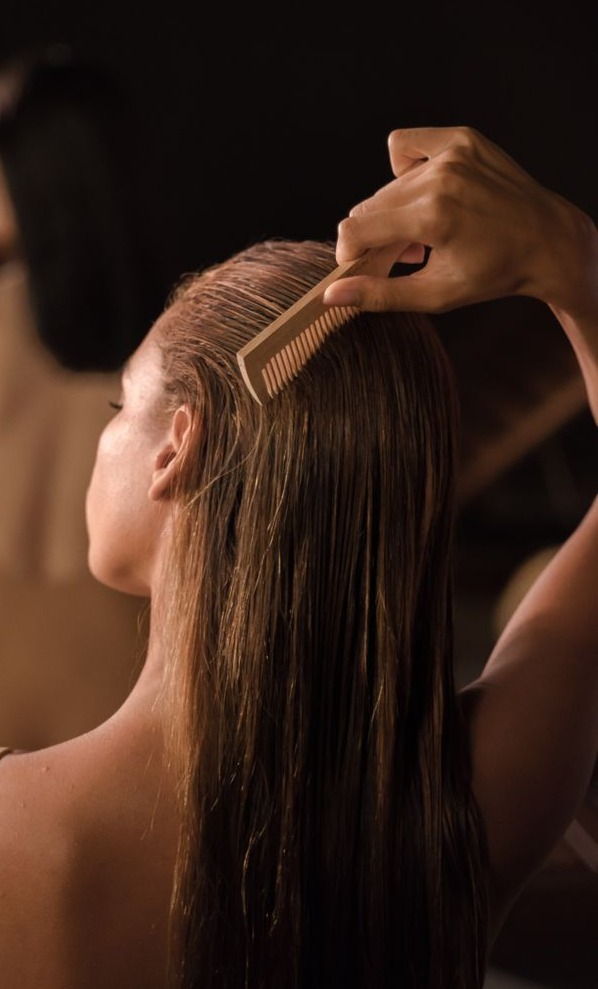 vue de dos de femmes soignant leurs cheveux avec des peignes dans un cadre spa serein promouvant le soin de soi