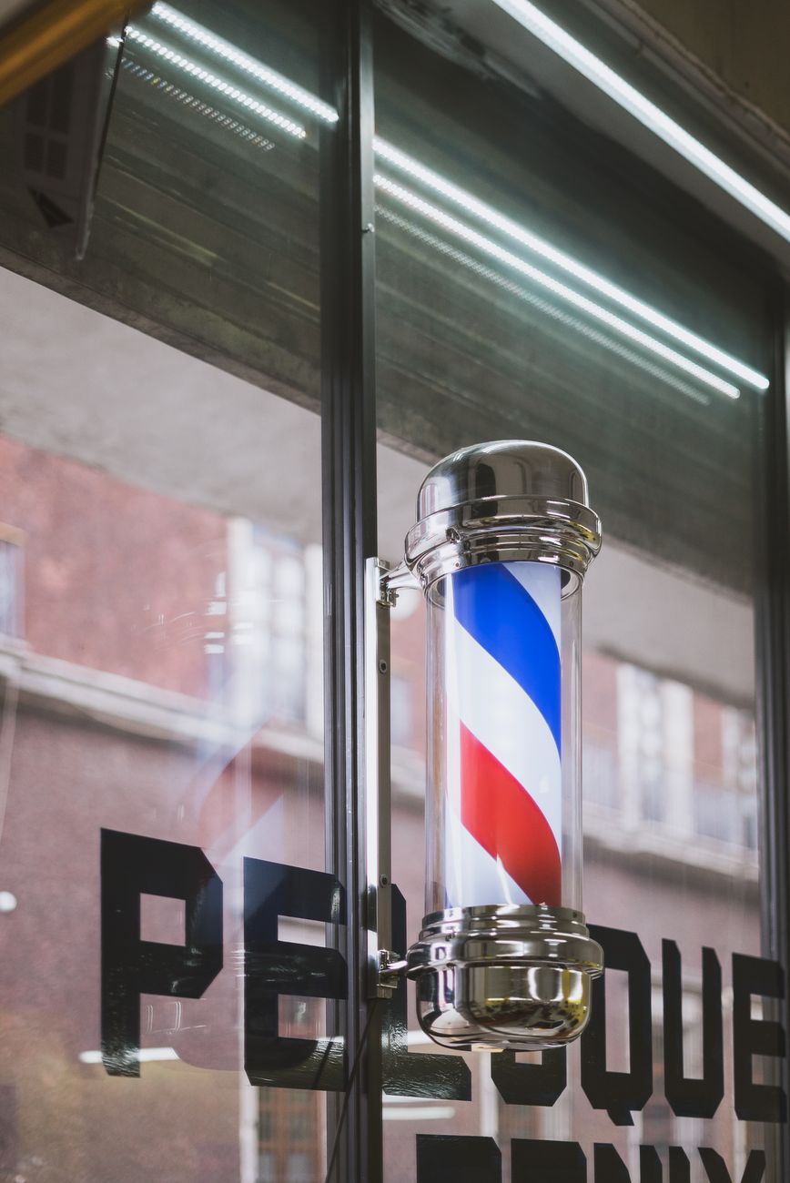 un poteau de barbier avec des rayures rouges blanches et bleues emblematiques a l exterieur d un salon de coiffure