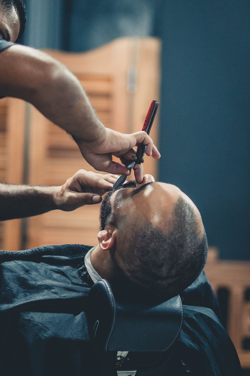 gros plan sur un barbier qui rase habilement la barbe d un homme a l interieur mettant en avant precision et soin