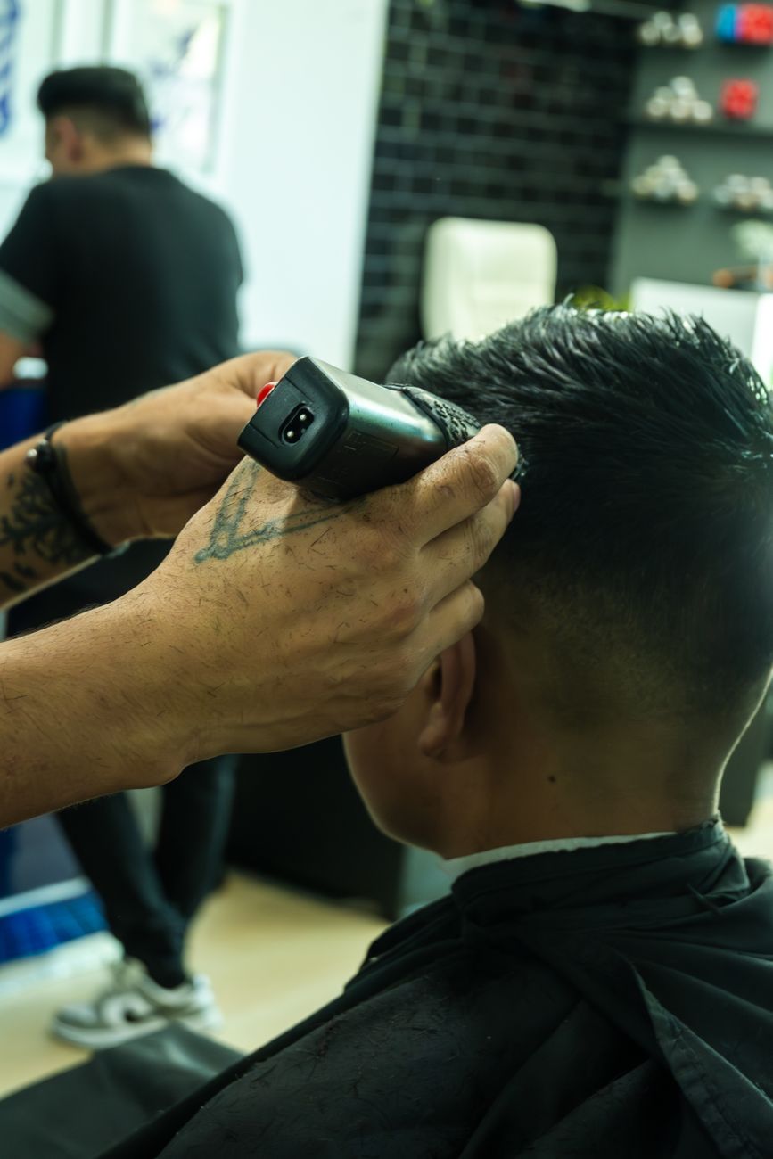 gros plan d un coiffeur utilisant une tondeuse pour couper les cheveux d un client dans un salon de coiffure moderne