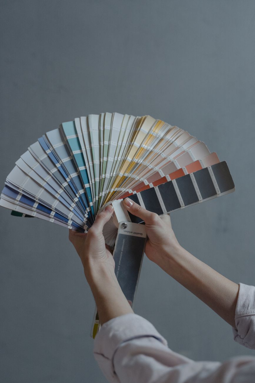 des mains tenant des echantillons de couleur en forme d eventail sur un fond gris