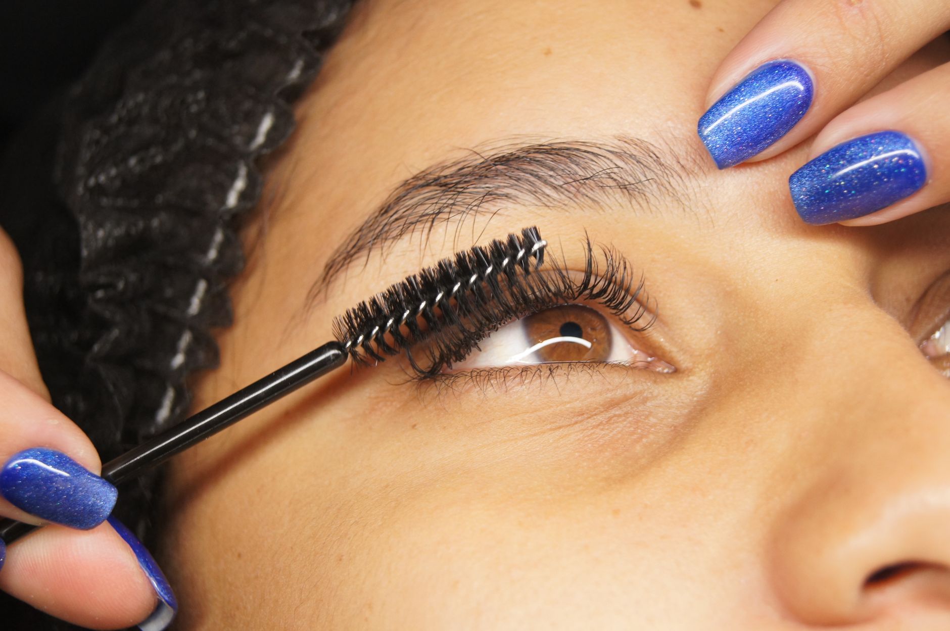 gros plan detaille de la pose d extensions de cils sur une femme aux ongles peints en bleu