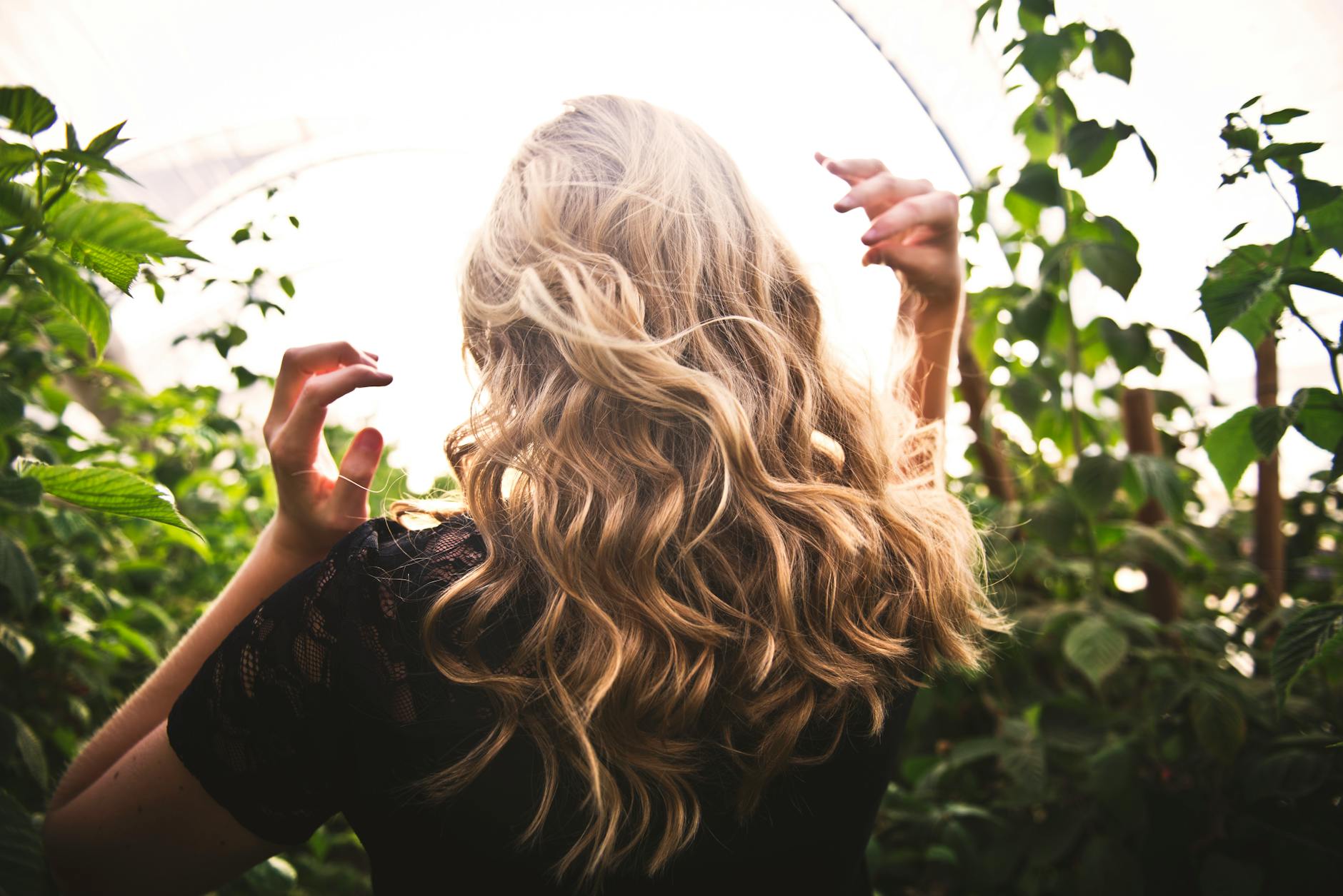 femme aux cheveux blonds debout entre les plantes vertes