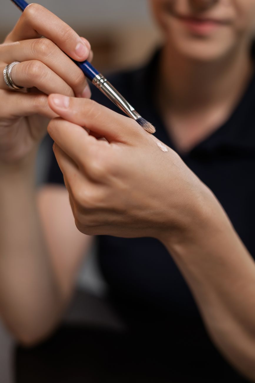 gros plan d une femme appliquant du maquillage avec un pinceau a la main a l interieur