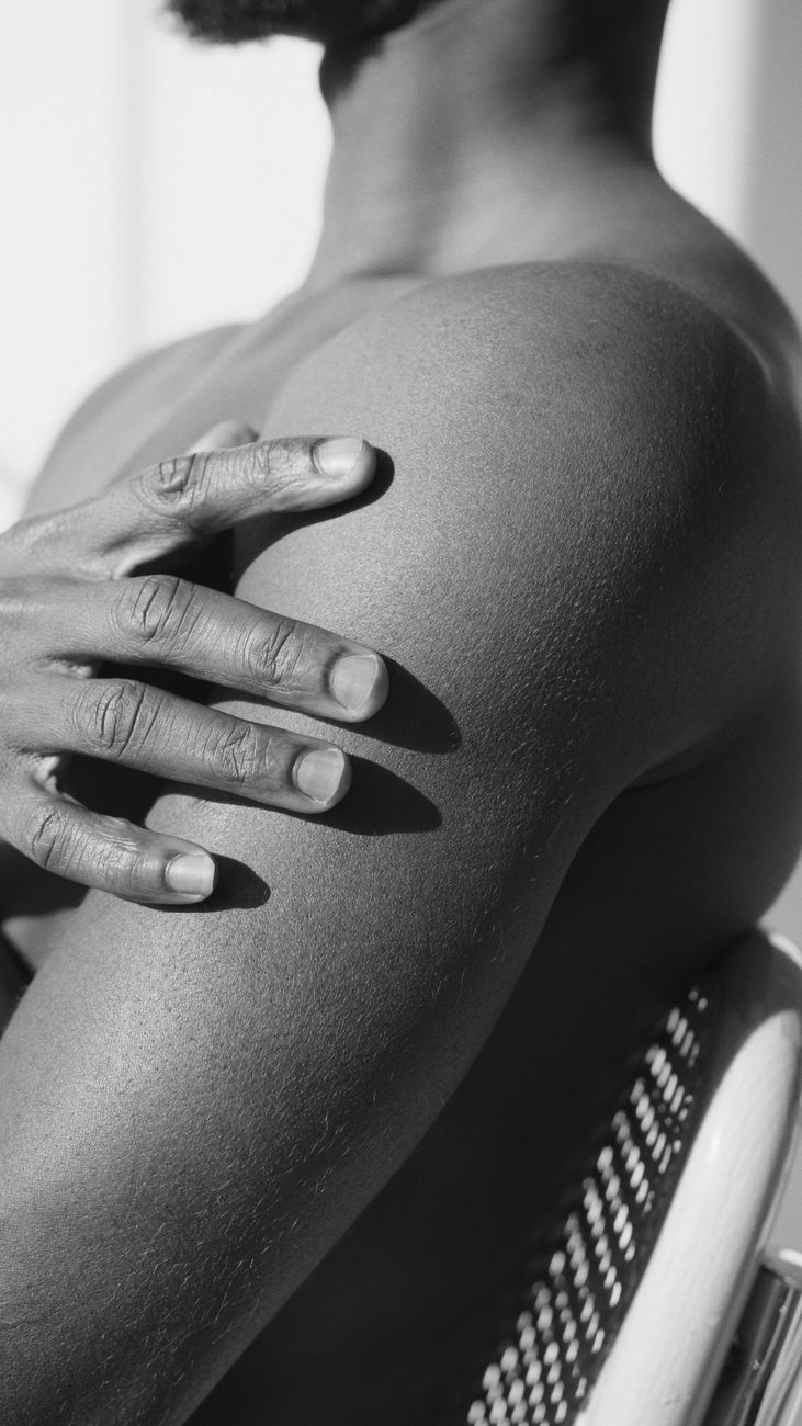 un gros plan en noir et blanc d une personne touchant doucement son epaule mettant en evidence la texture