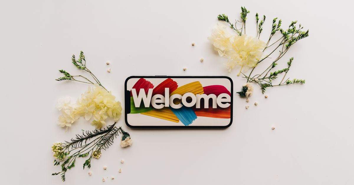 composition creative a plat avec un smartphone affichant un panneau de bienvenue colore entoure de fleurs delicates