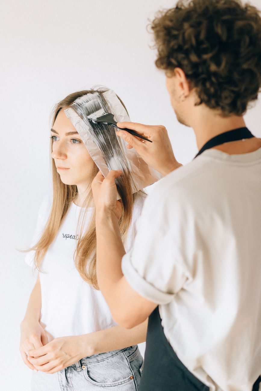 un coiffeur appliquant de la teinture sur les cheveux d une cliente dans un salon mettant en avant le moderne soin de soi