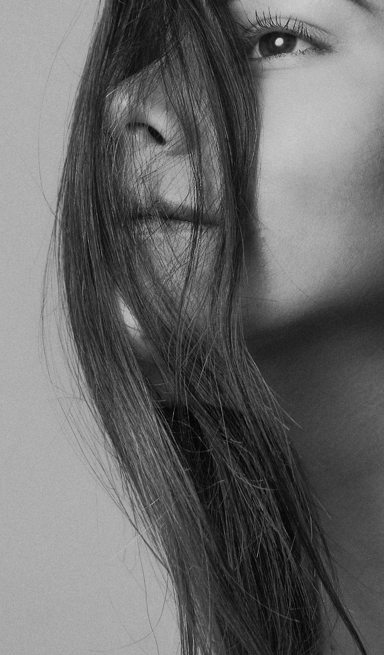 portrait en gros plan en niveaux de gris d une jeune femme avec des cheveux couvrant partiellement son visage capturant une ambiance artistique