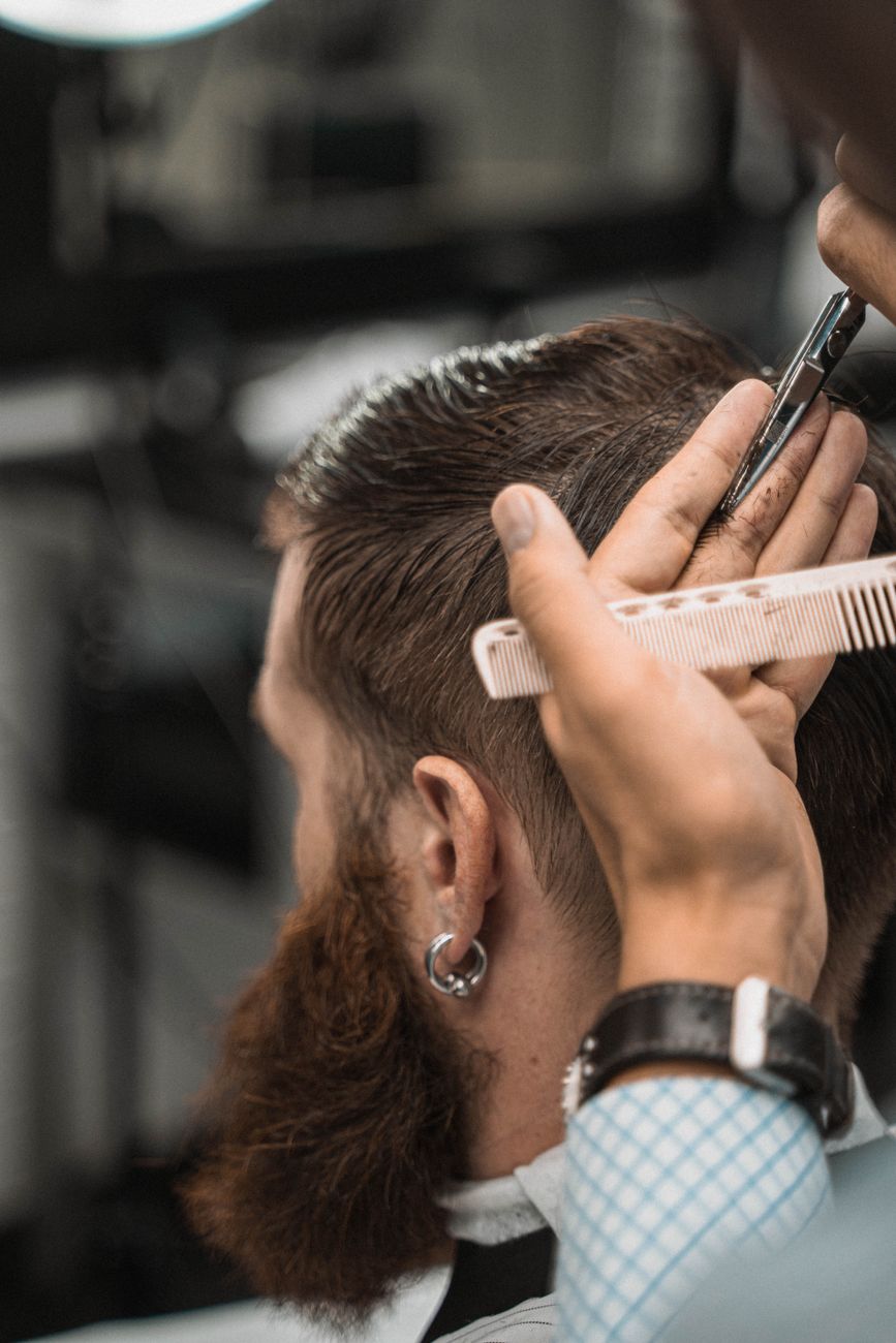 gros plan sur un coiffeur coupant les cheveux d un homme avec des ciseaux et un peigne dans un cadre style