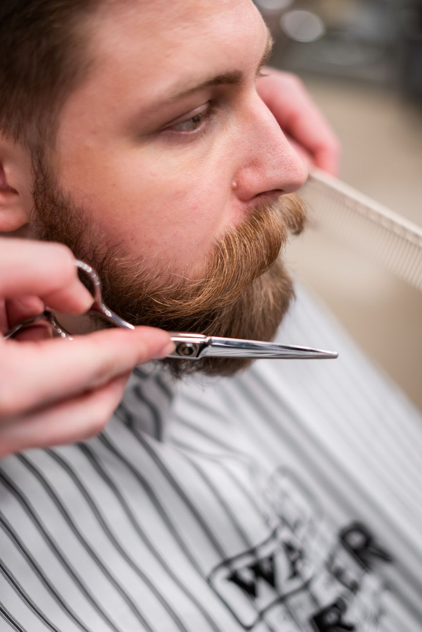 gros plan d un coiffeur taillant la barbe et la moustache d un homme barbu avec des ciseaux