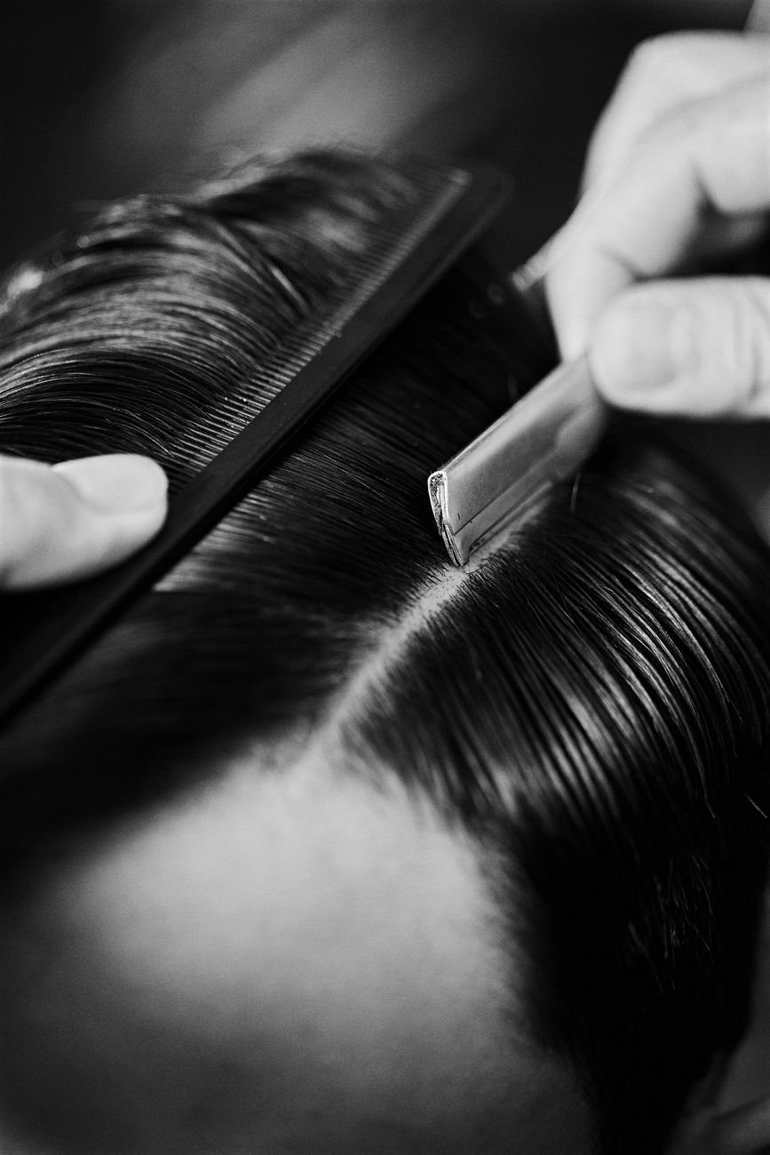 gros plan en noir et blanc sur le coiffage avec un peigne et un rasoir dans un barber shop