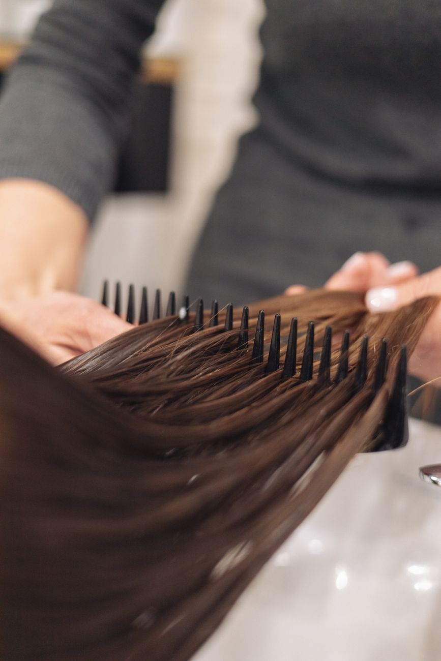 un coiffeur peigne habilement des cheveux mouilles se concentrant sur un coiffage lisse dans un cadre de salon