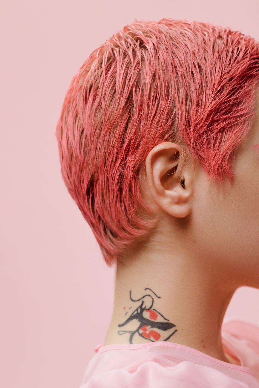 un portrait frappant mettant en avant une personne aux cheveux roses avec un tatouage unique au cou