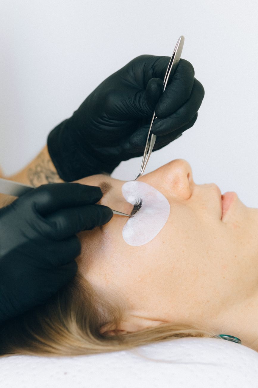 gros plan sur une estheticienne appliquant des extensions de cils a une cliente dans un salon