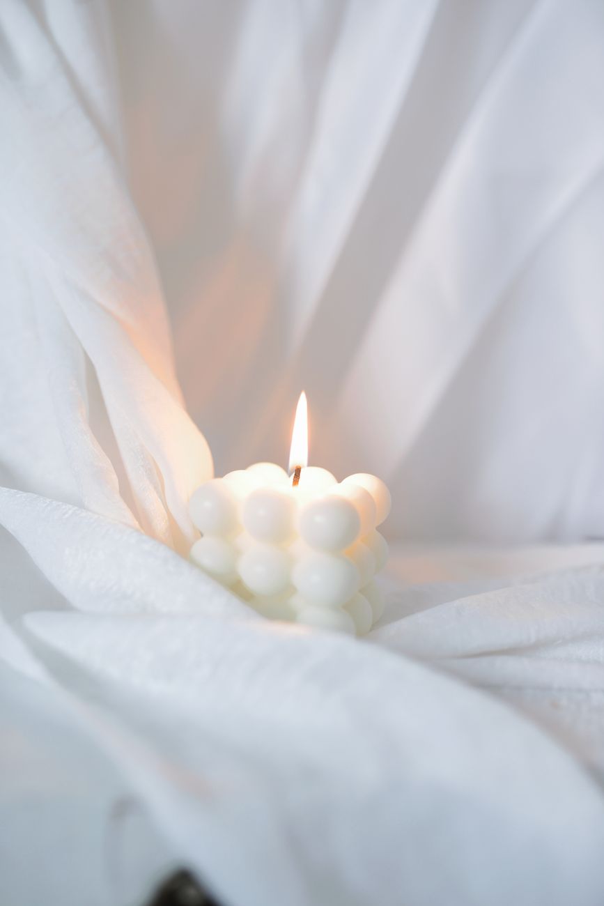 une bougie bulle allumee sur un doux tissu blanc creant une ambiance apaisante et chaleureuse