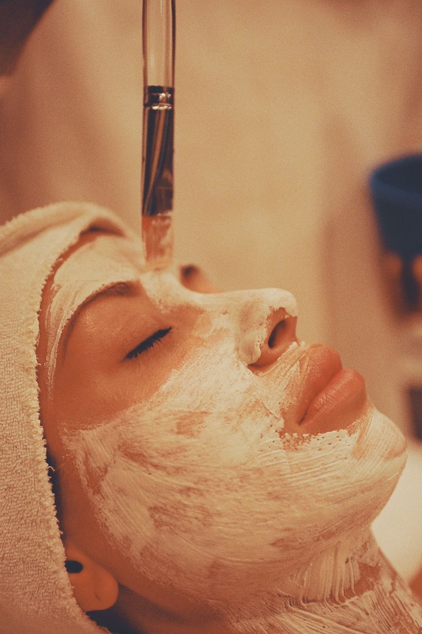 femme adulte recevant un masque facial apaisant dans un spa moderne