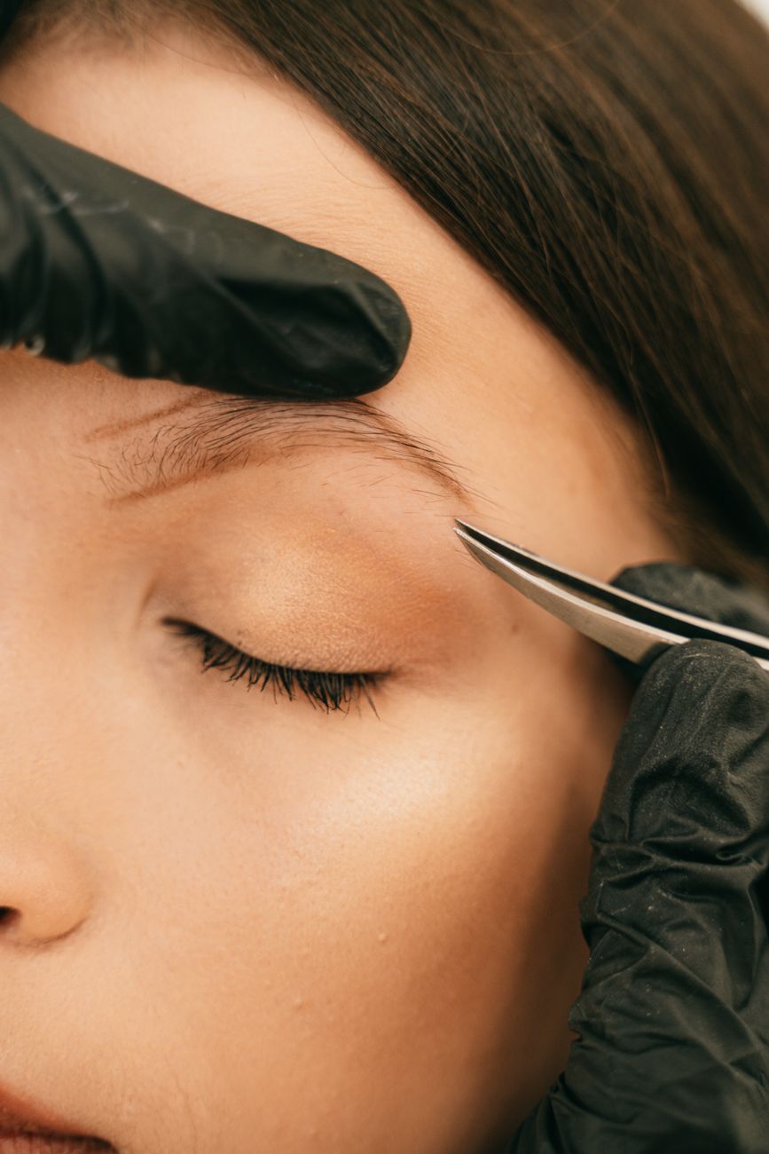 un gros plan detaille d une femme ayant son sourcil sculpte avec des pinces a epiler mettant en valeur les soins de beaute professionnels